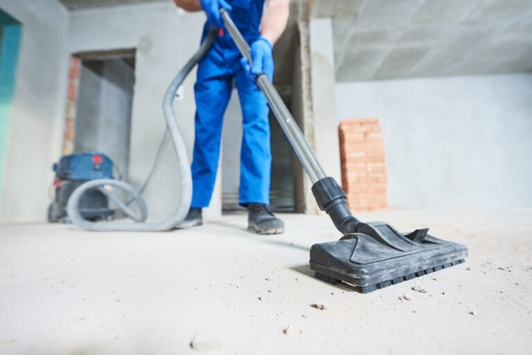 Bauendreinigung: Arbeiter saugt Baustellenstaub mit einem Industriesauger.