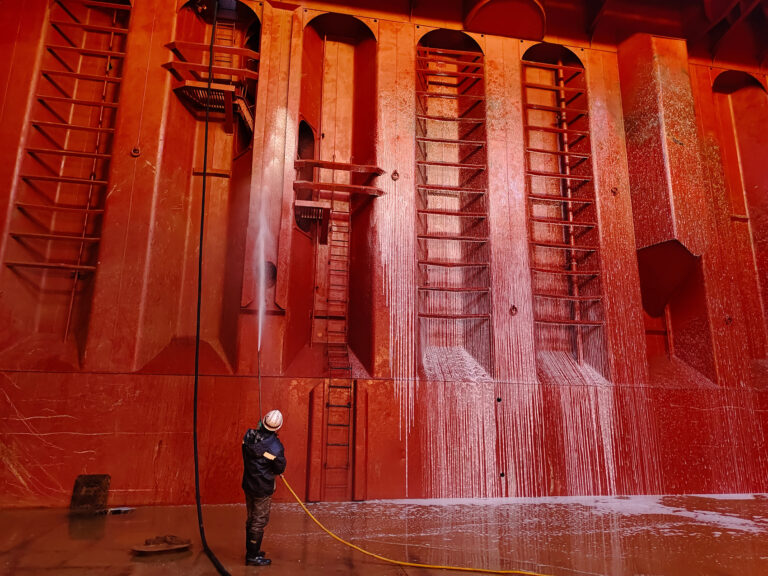Große rote Fassade wird mit Hochdruck gereinigt.