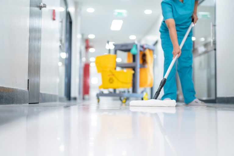 Mitarbeiterin wischt Krankenhaus Boden.